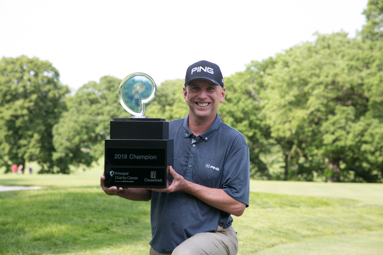 golfer Dan Sutherland kneeling and posing with 2019 Champion trophy